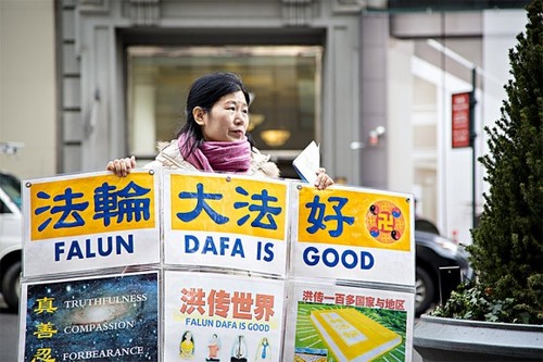 Ванг Хуиџуан, пред зградата на Емпери Стејт во Менхетен, Њујорк, на 12. јануари 2017 година, држи во рацете постер за да им помогне на кинеските туристи да ги разберат фактите за прогонот на Фалун Гонг во Кина.  (Самира Буау / Епох Тајмс)